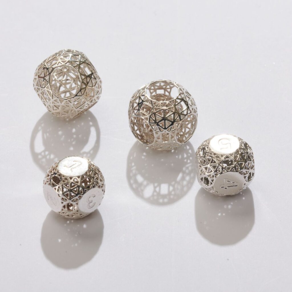 Showcase of four intricately cast spherical designs in natural and polished silver, highlighting the reflective sheen and fine geometric detailing of sterling silver