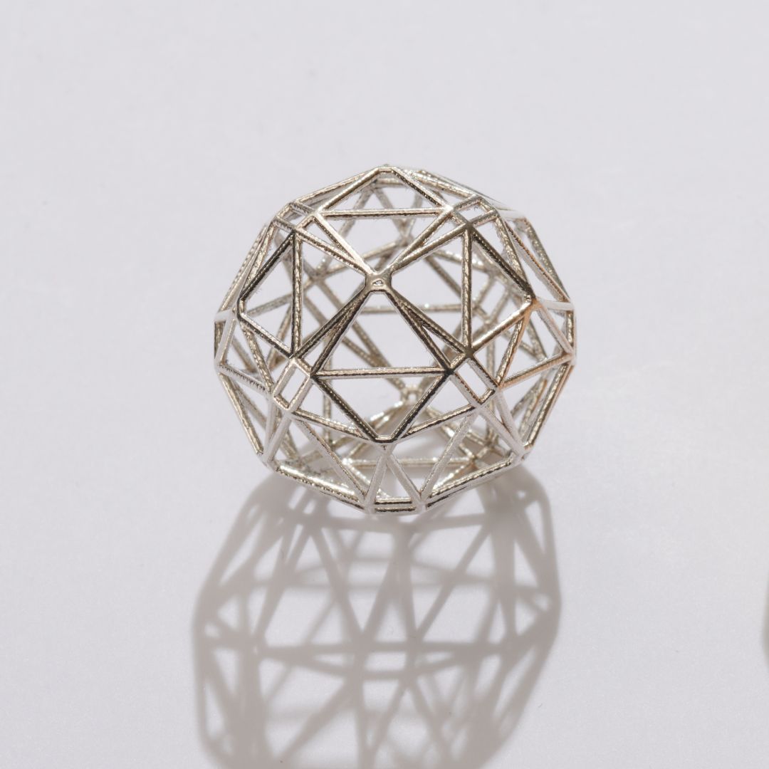 Geometric silver sphere made with lost wax casting, featuring an open lattice structure