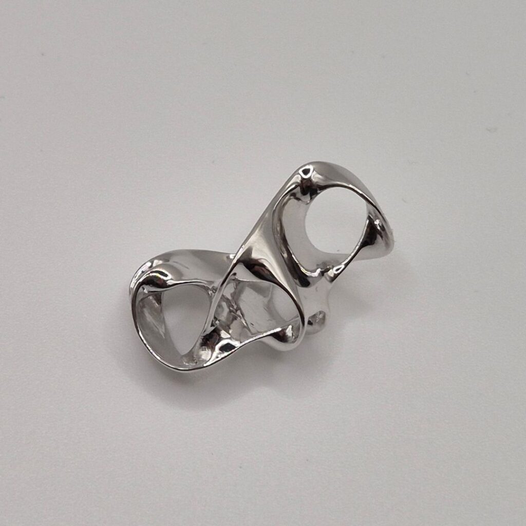 Showcase of a Highly reflective, chrome-plated brass casting with interlocking ring design, showcasing the sleek, mirror-like finish of 0.5 micron electroplating.