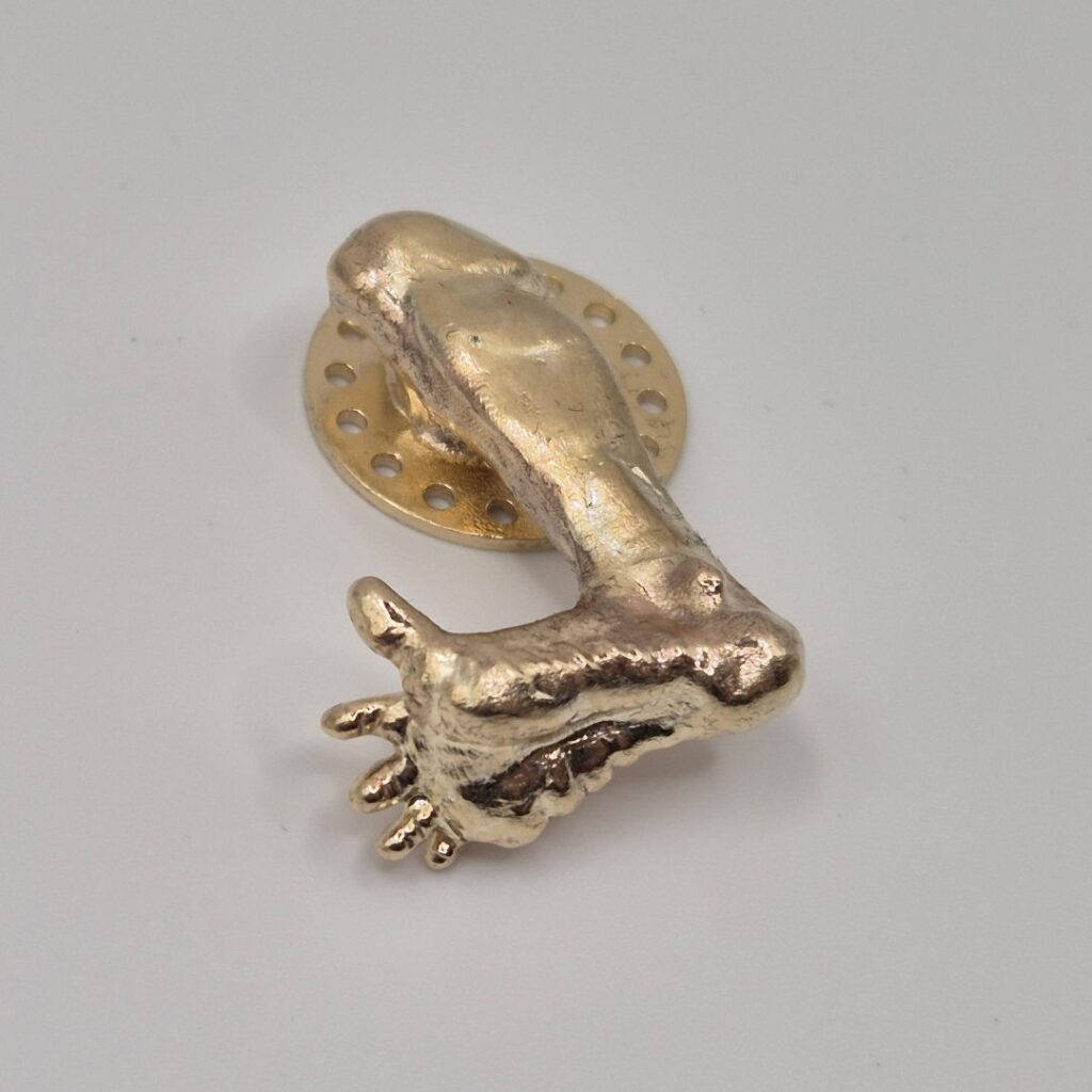 Showcase of a detailed brass casting of a foot-shaped design with natural finish.