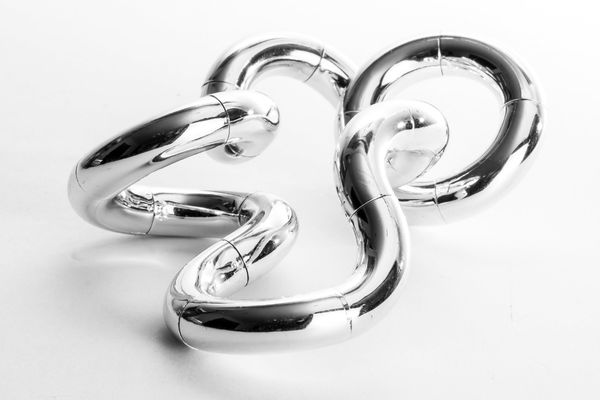 Oversized sculptural chain links in polished platinum finish with smooth reflective curve
