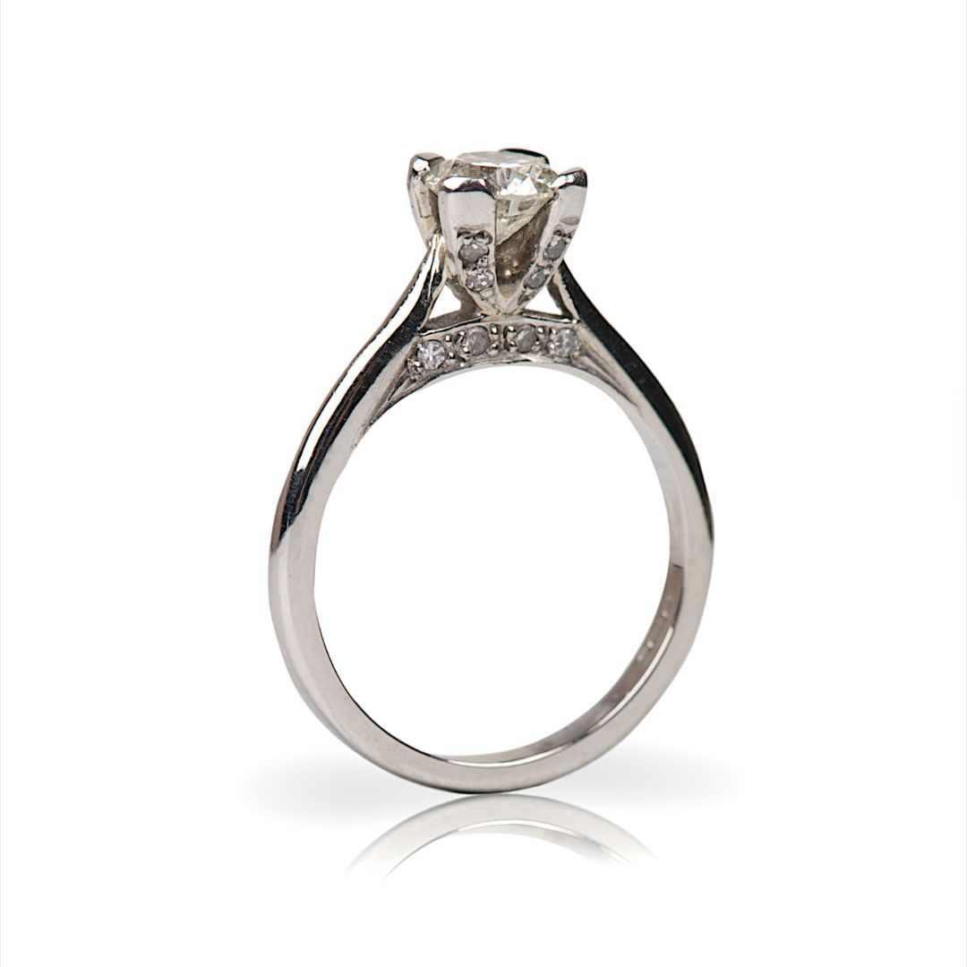 Platinum solitaire engagement ring with raised four-prong setting and side pavé diamonds