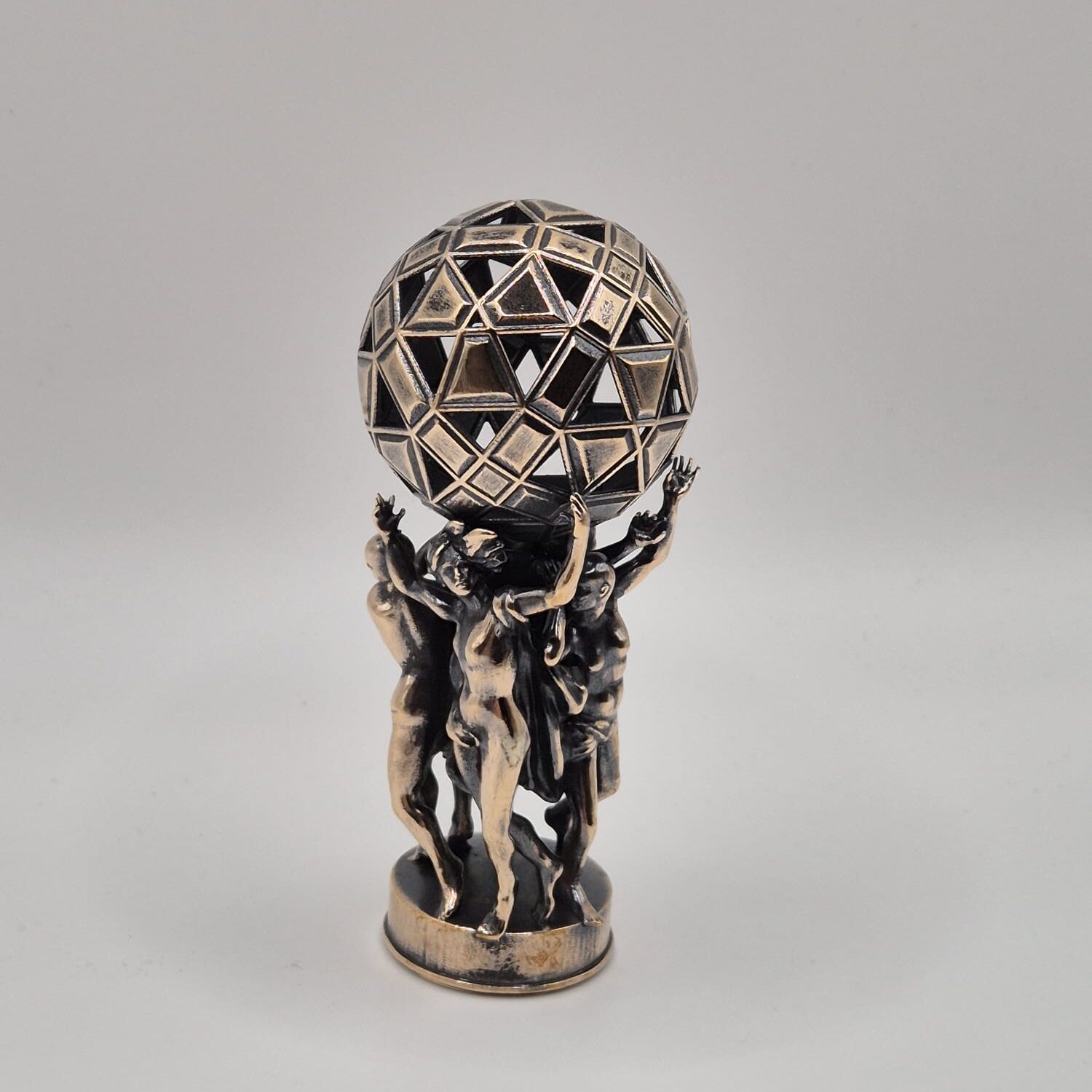 Antique bronze figurine holding geometric sphere