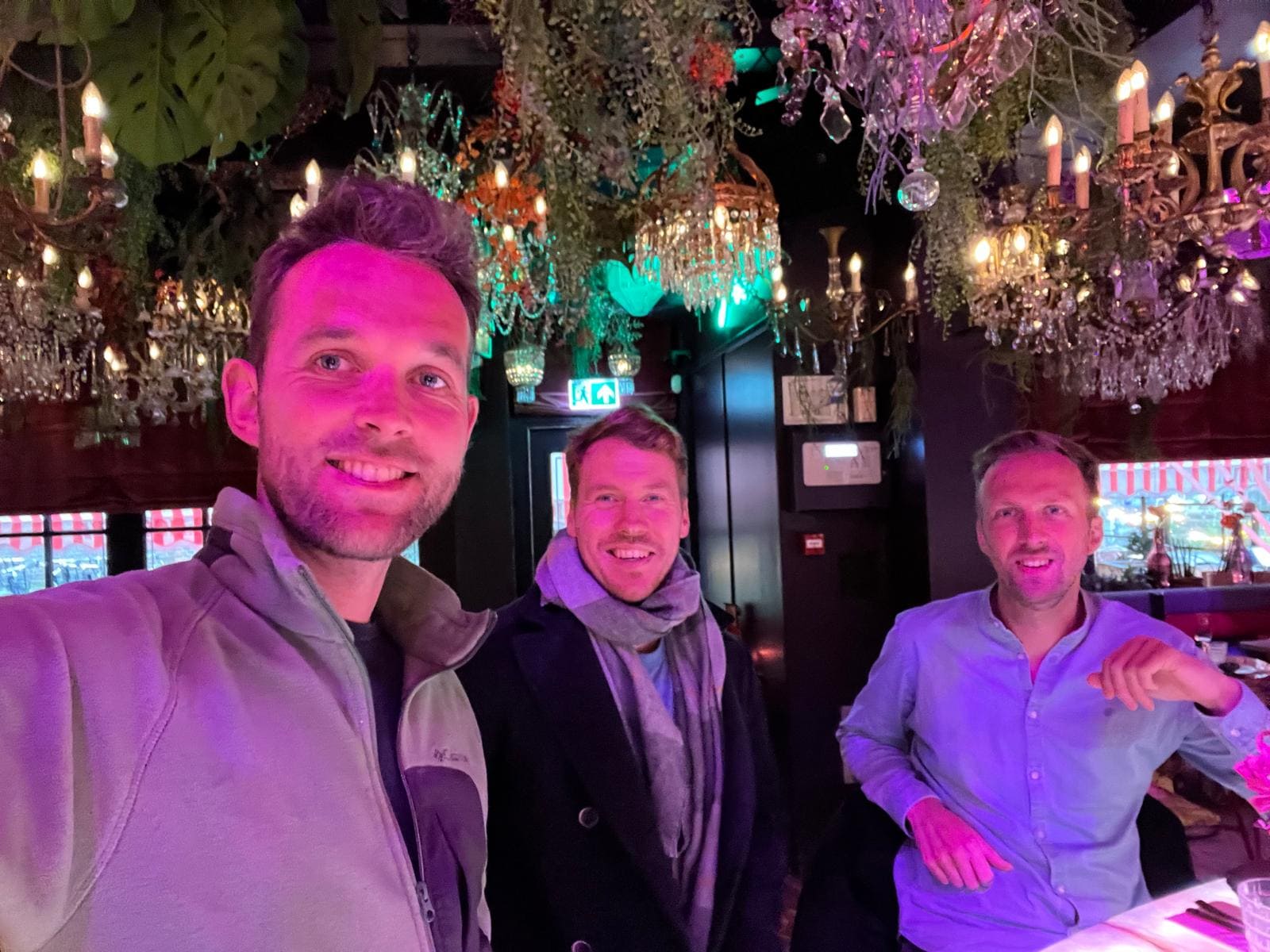 The three co-founders of team Castimize at a warmly lit venue with chandeliers